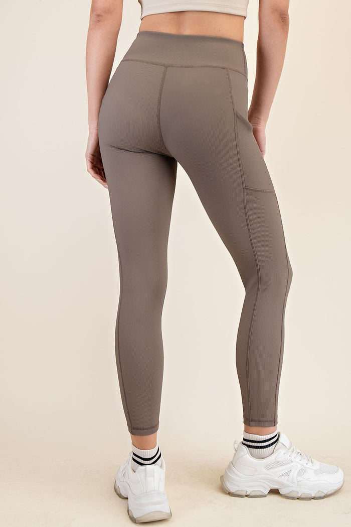 woman wearing light brown high-waisted leggings with a ribbed texture and side pockets, showing the back view