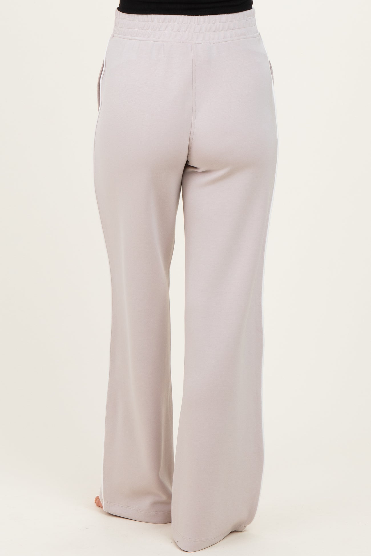 woman wearing light grey maternity pants with a relaxed fit and elastic waist from the back