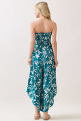woman wearing a teal strapless jumpsuit with white floral print and a high-low hemline, viewed from the back