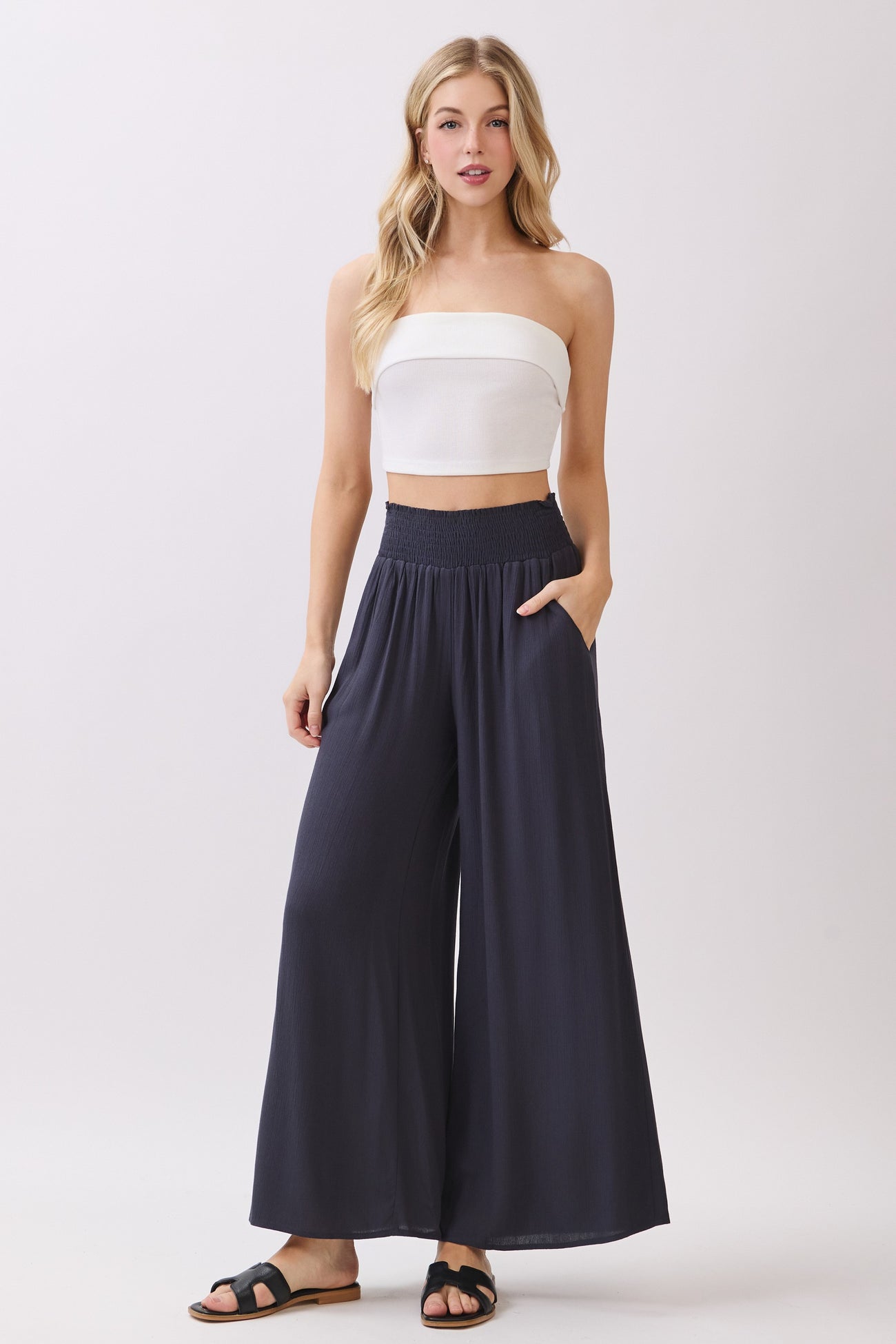 woman wearing a white strapless top and navy wide-leg pants with pockets