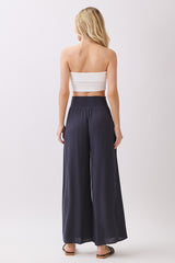 woman wearing a white strapless top and dark gray wide-leg pants seen from the back