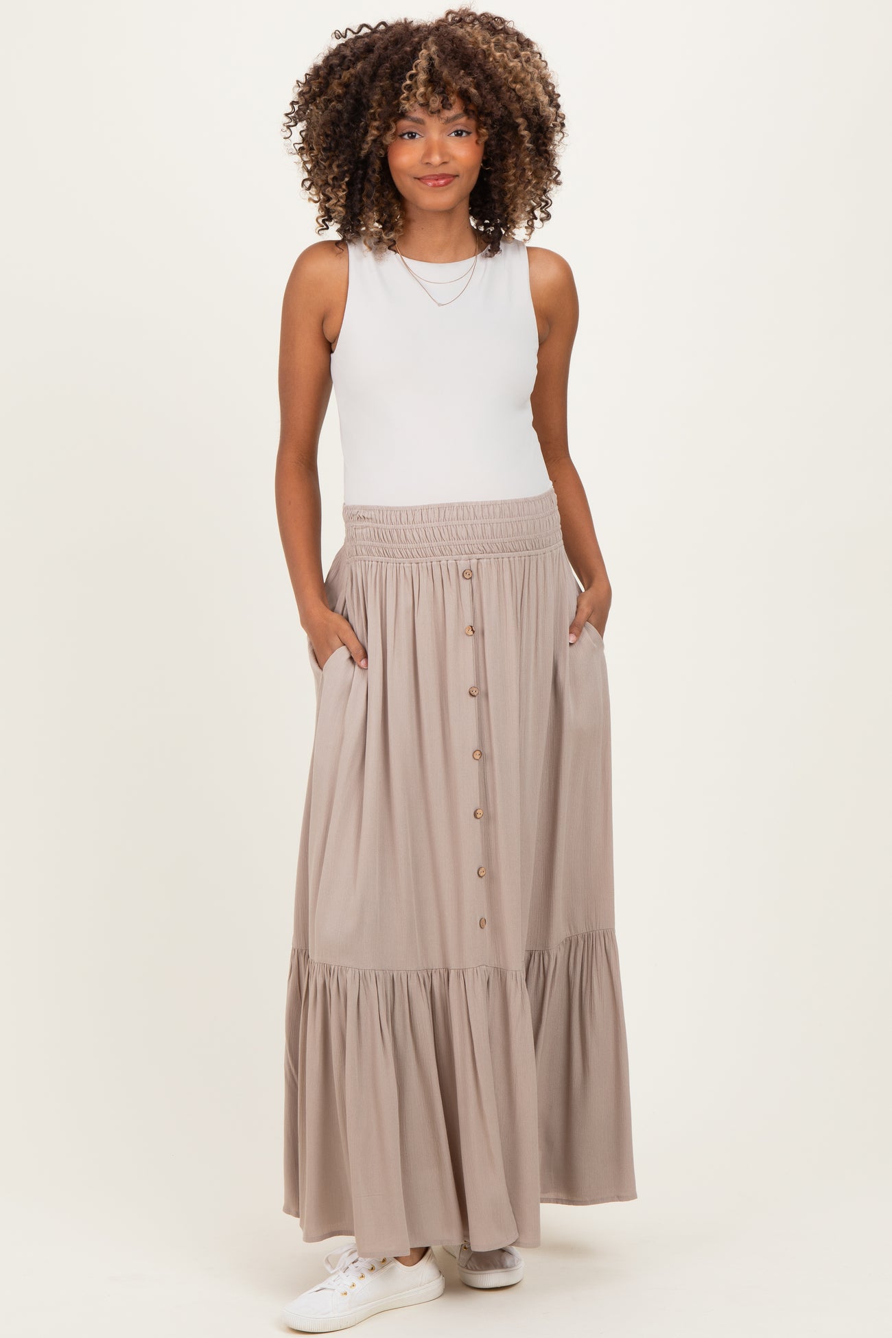 woman wearing a white tank top and a beige maternity maxi skirt with buttons, styled with pockets and a tiered hem