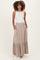 woman wearing a white tank top and a beige maternity maxi skirt with buttons, styled with pockets and a tiered hem