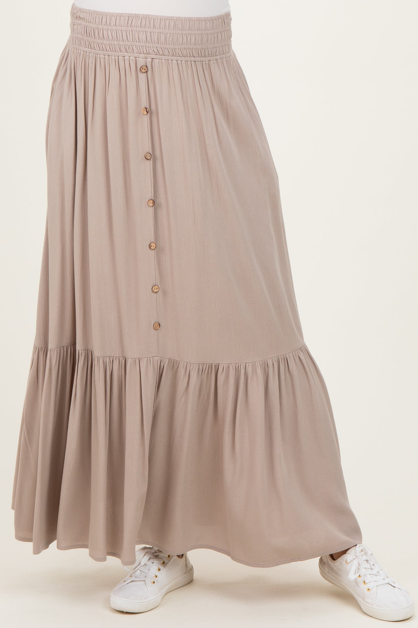 maternity wear in a taupe maxi skirt with a tiered design and button detailing, paired with white sneakers