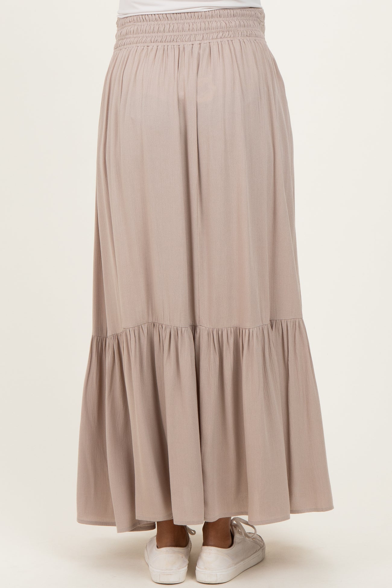 woman wearing a flowy beige maternity maxi skirt with a tiered ruffle hem and elastic waistband