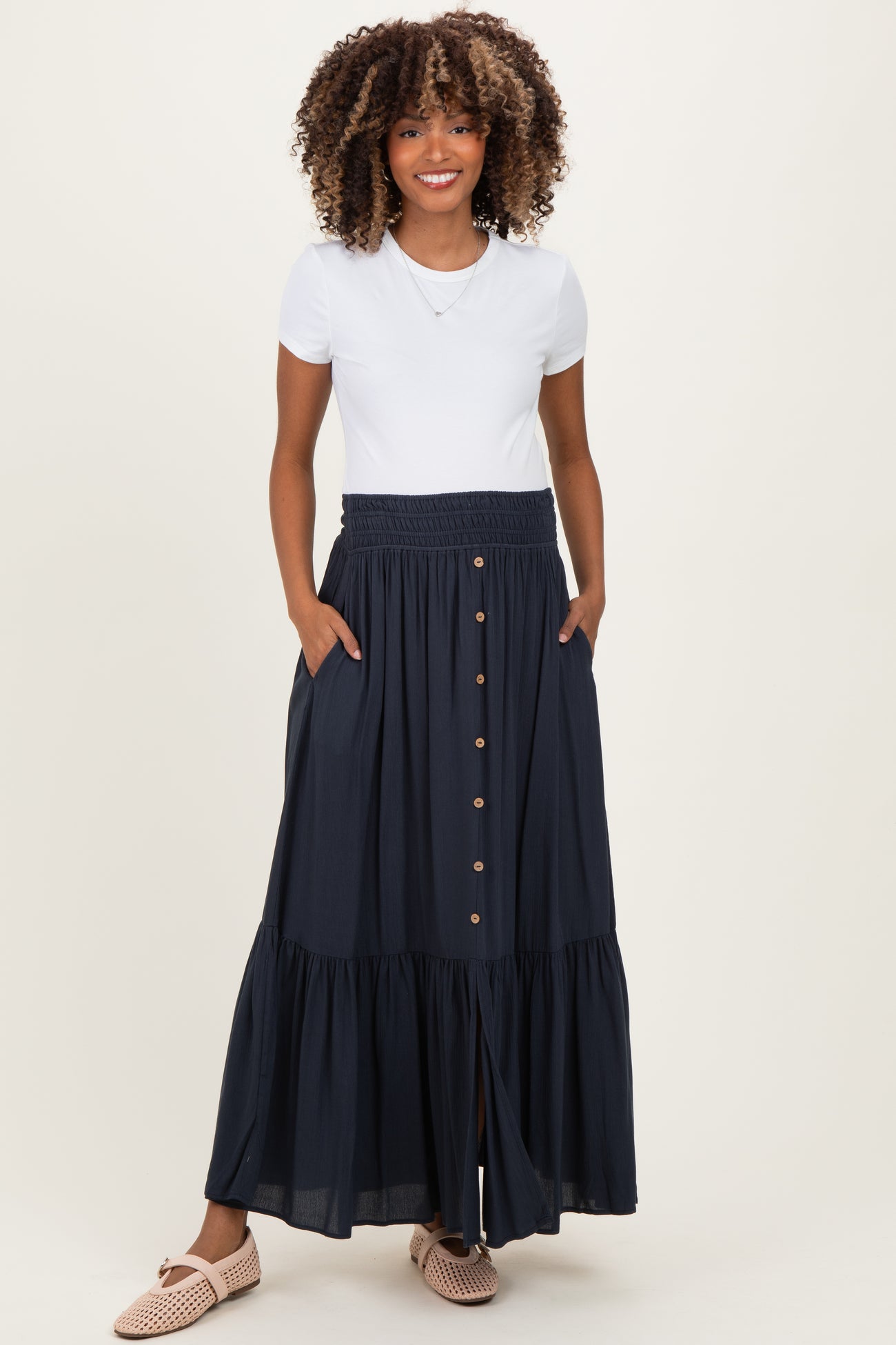 woman wearing a white short sleeve top and a navy blue maternity maxi skirt with buttons and pockets