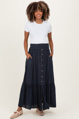 woman wearing a white short sleeve top and a navy blue maternity maxi skirt with buttons and pockets