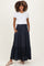woman wearing a white short sleeve top and a navy blue maternity maxi skirt with buttons and pockets