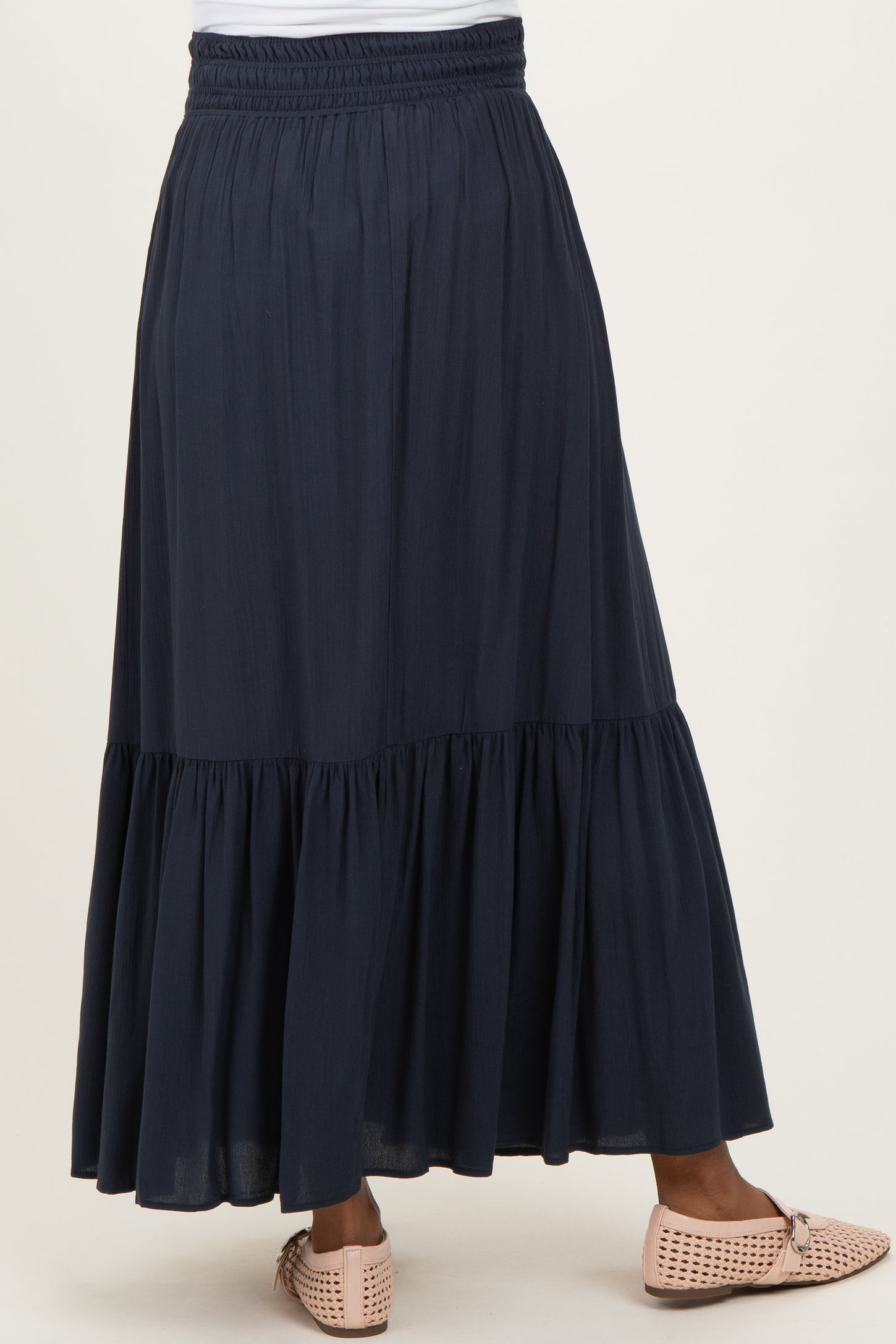 woman wearing a navy blue maternity maxi skirt with a tiered design and elastic waistband
