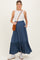 woman wearing a navy blue maternity maxi skirt with buttons and pockets, paired with a white tank top and holding a bag