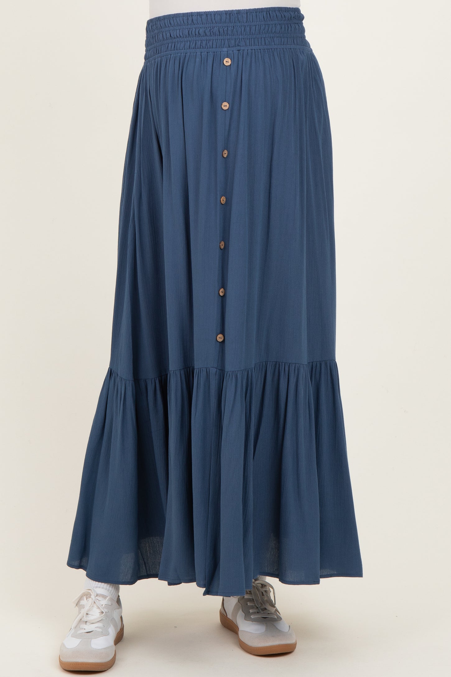 woman wearing a blue maternity maxi skirt with a tiered hem and button detailing