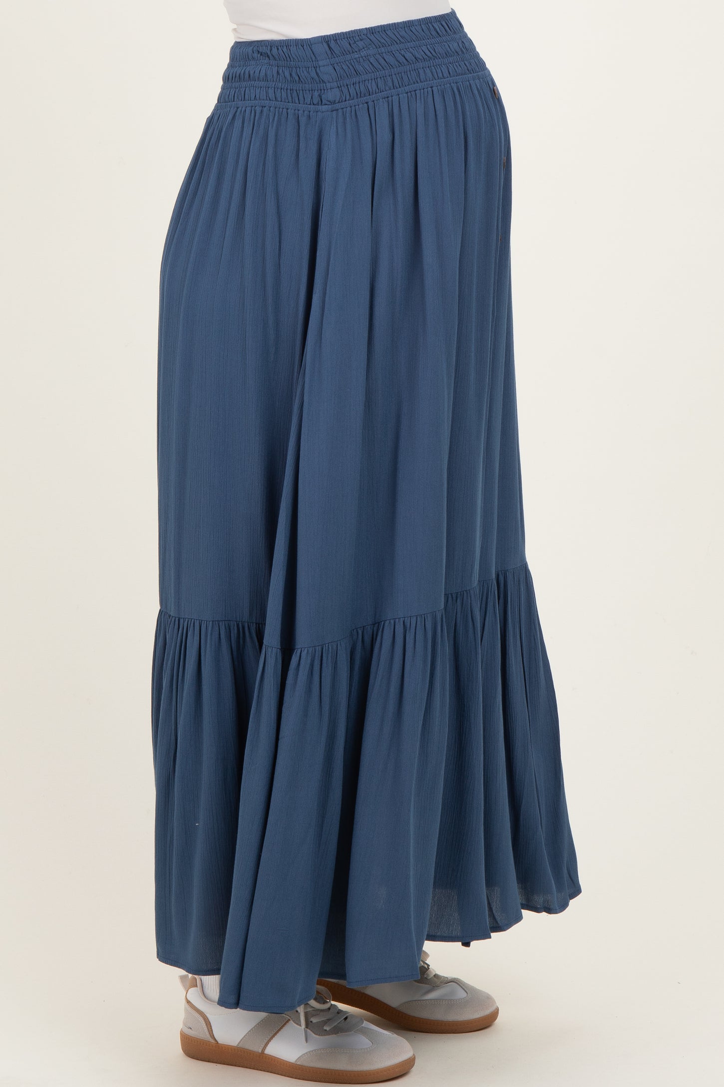 woman wearing a navy blue maternity maxi skirt with a tiered ruffle design and a comfortable waistband