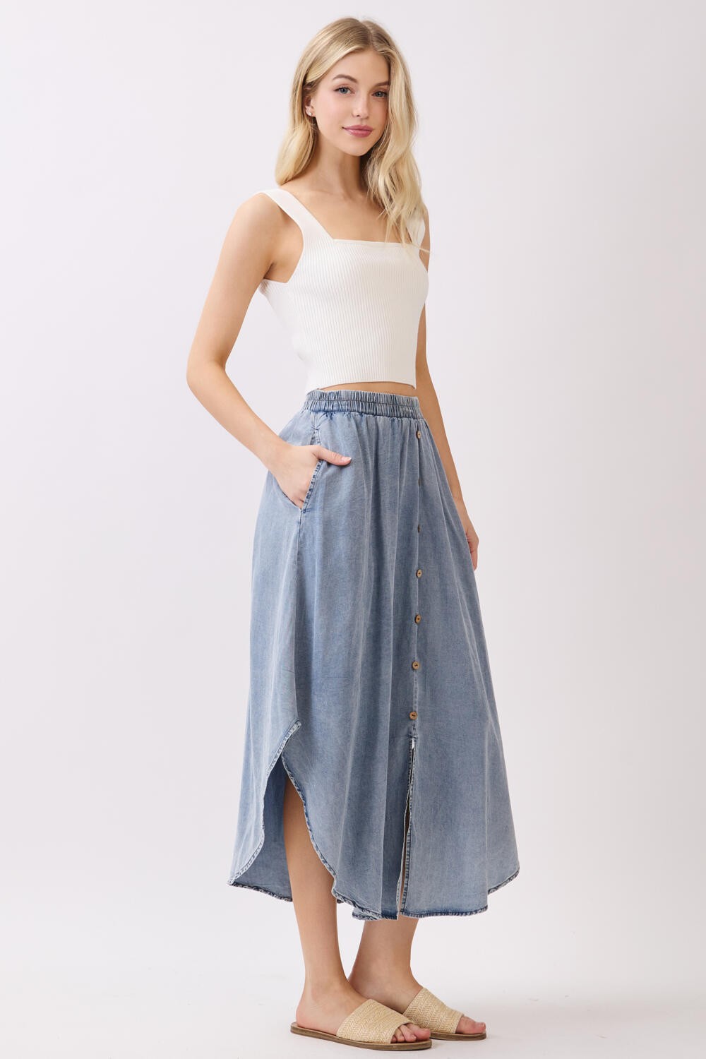 woman wearing a white ribbed crop top and a light blue button-up denim maxi skirt with pockets