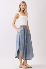 woman wearing a white ribbed crop top and a light blue button-up denim maxi skirt with pockets