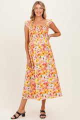 woman wearing a colorful floral print maternity maxi dress with smocked details and cap sleeves