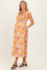 woman wearing a floral maternity dress with a smocked bodice and pockets, showcasing her baby bump