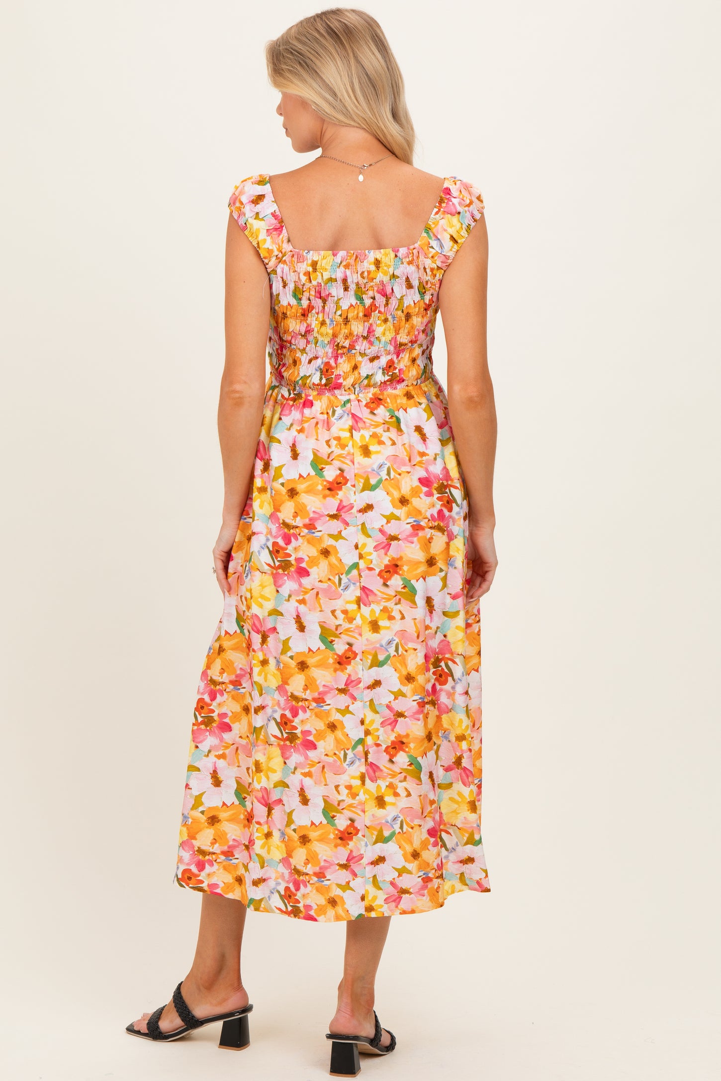woman wearing a floral maternity dress with a smocked bodice and midi length, showing a baby bump from the back