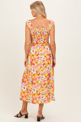 woman wearing a floral maternity dress with a smocked bodice and midi length, showing a baby bump from the back