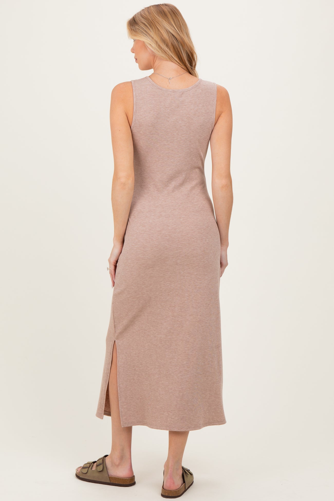 woman wearing a mauve ribbed maxi maternity dress with a side slit, showing her back and wearing slide sandals