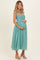woman wearing a green and white gingham maternity dress with tie straps and a visible baby bump