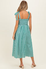 woman wearing a green and white gingham maternity dress with tie shoulder straps and a smocked back