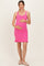 woman wearing a pink maternity dress with a ribbed texture and ruffled hem, holding her baby bump
