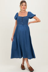 woman wearing a blue maternity dress with a smocked bodice, puff sleeves, and a flowing midi skirt