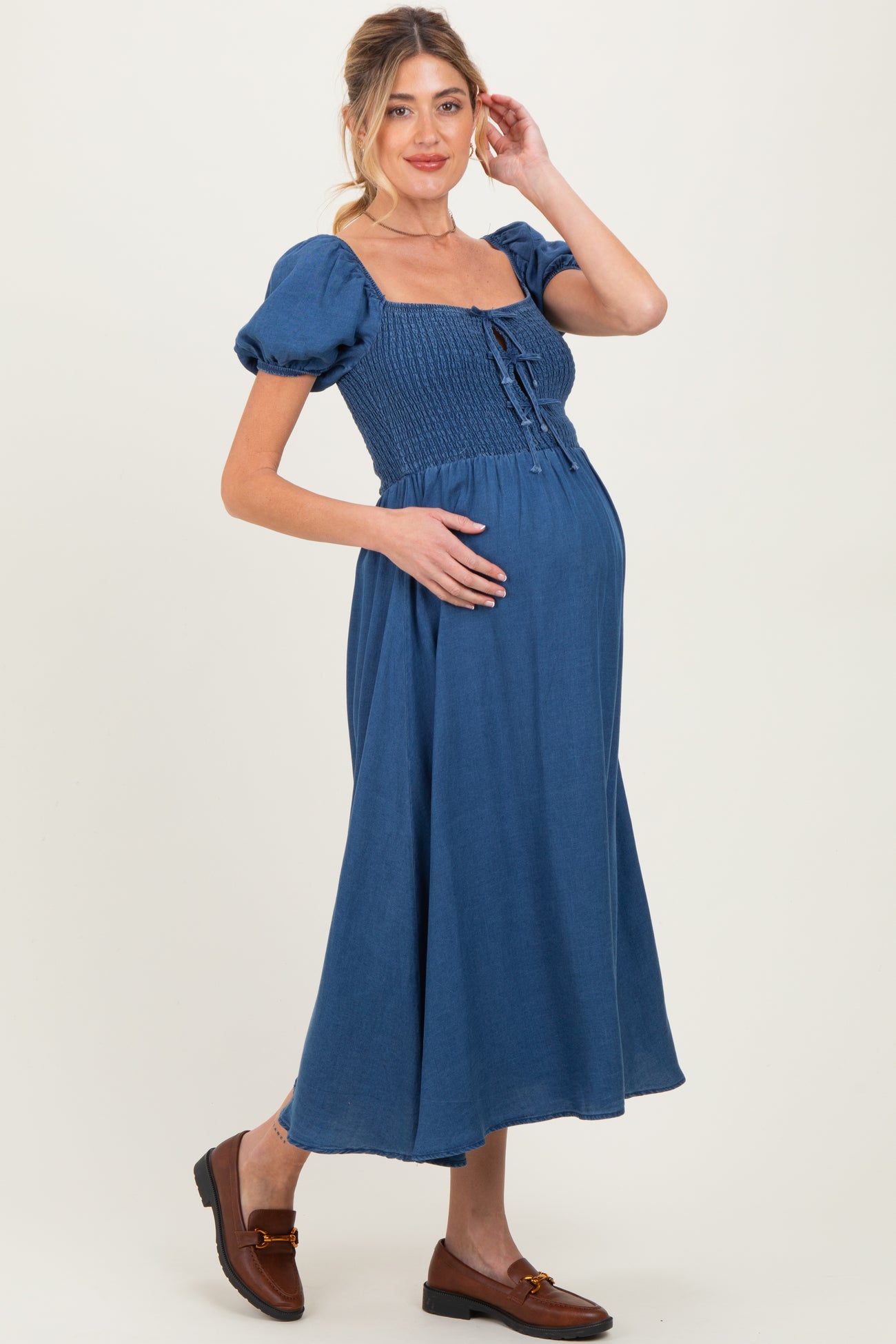 woman wearing a blue smocked maternity dress with short puff sleeves and a baby bump