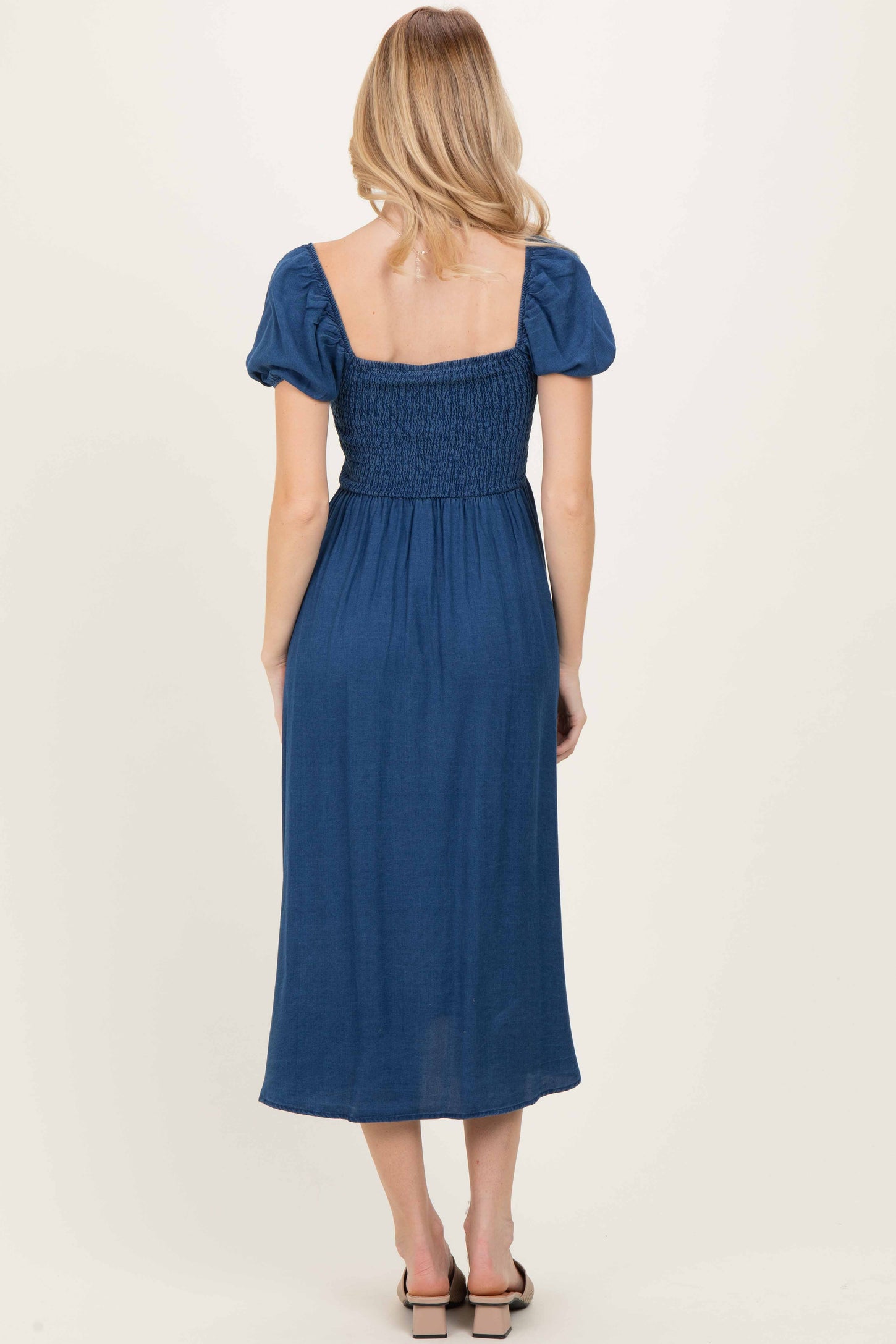 woman wearing a navy blue midi dress with puff sleeves and a smocked back design