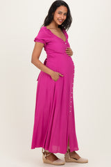 woman wearing a bright pink maternity maxi dress with short sleeves and pockets, showing her baby bump