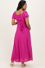 woman wearing a pink maternity maxi dress with puff sleeves and a tie back detail, showcasing a baby bump from the side