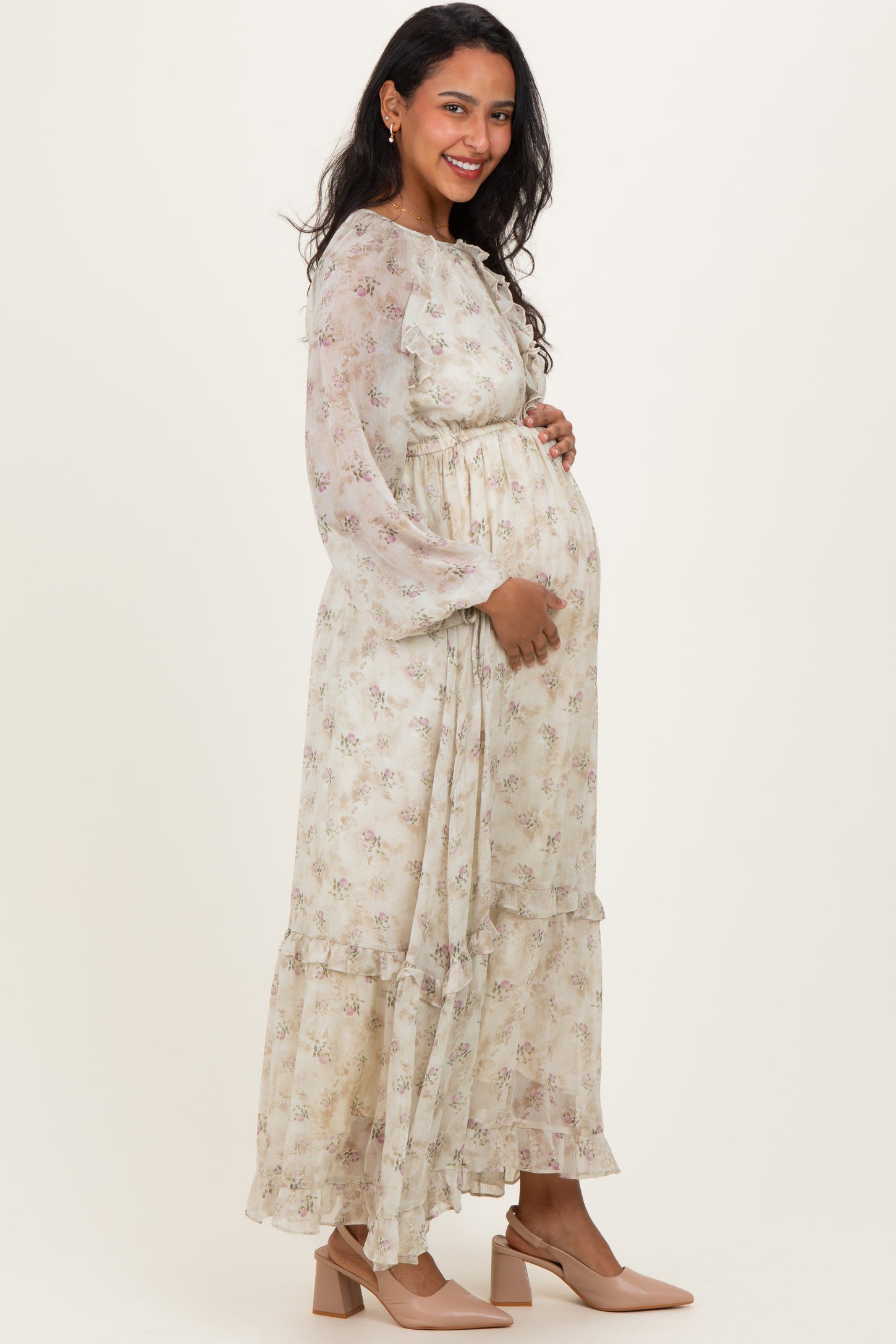 woman wearing a floral long sleeve maternity dress with a relaxed fit and ruffled hem, showing her baby bump