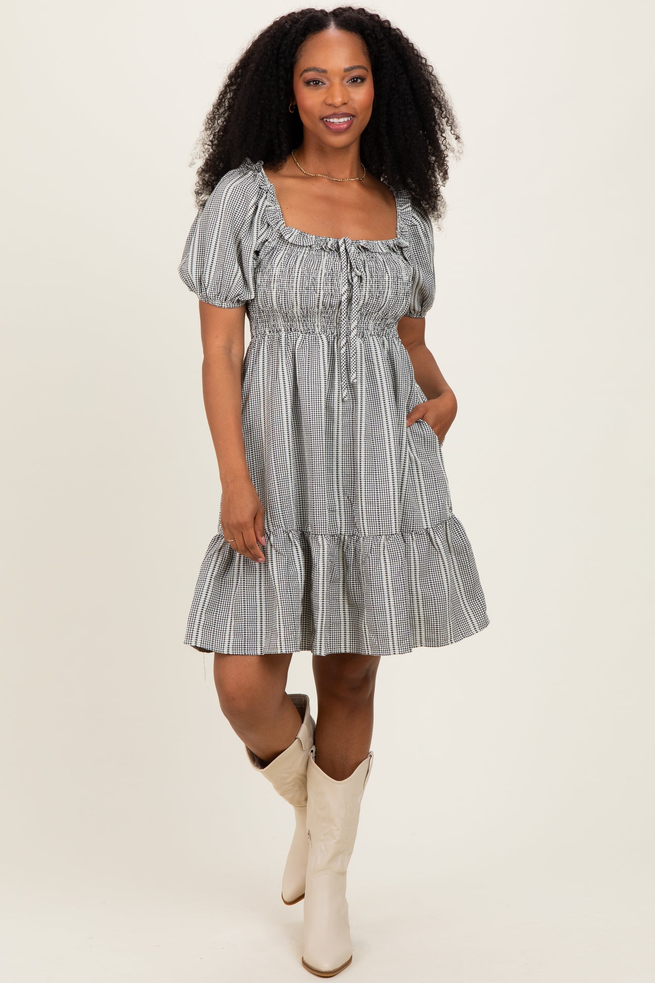 woman wearing a striped puff sleeve dress with a square neckline and ruffled hem, standing with one hand in the pocket