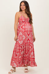 woman wearing a red floral maternity maxi dress with adjustable straps and a flowing skirt, showcasing her baby bump