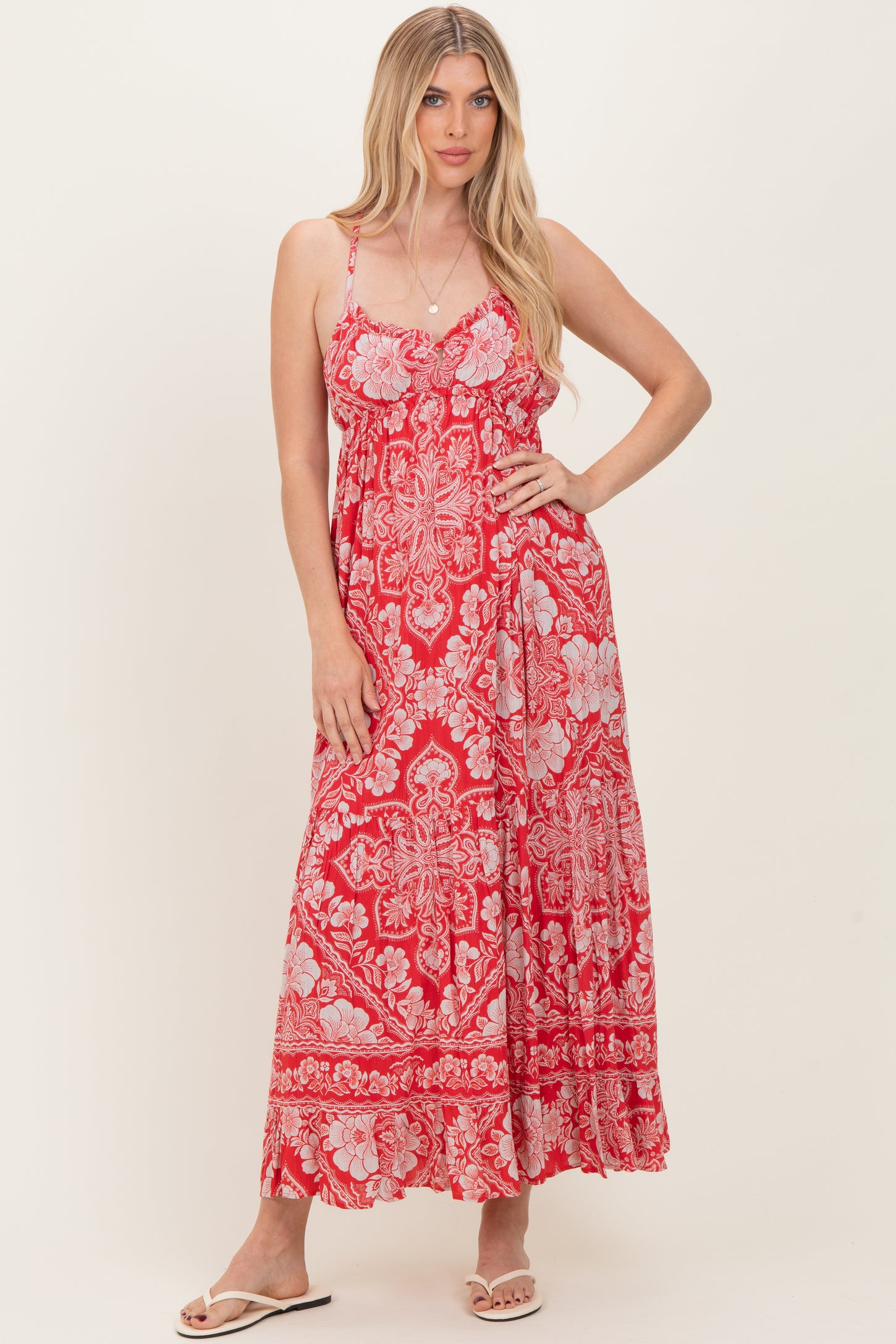 woman wearing a red patterned maxi dress with thin straps and a flowing silhouette
