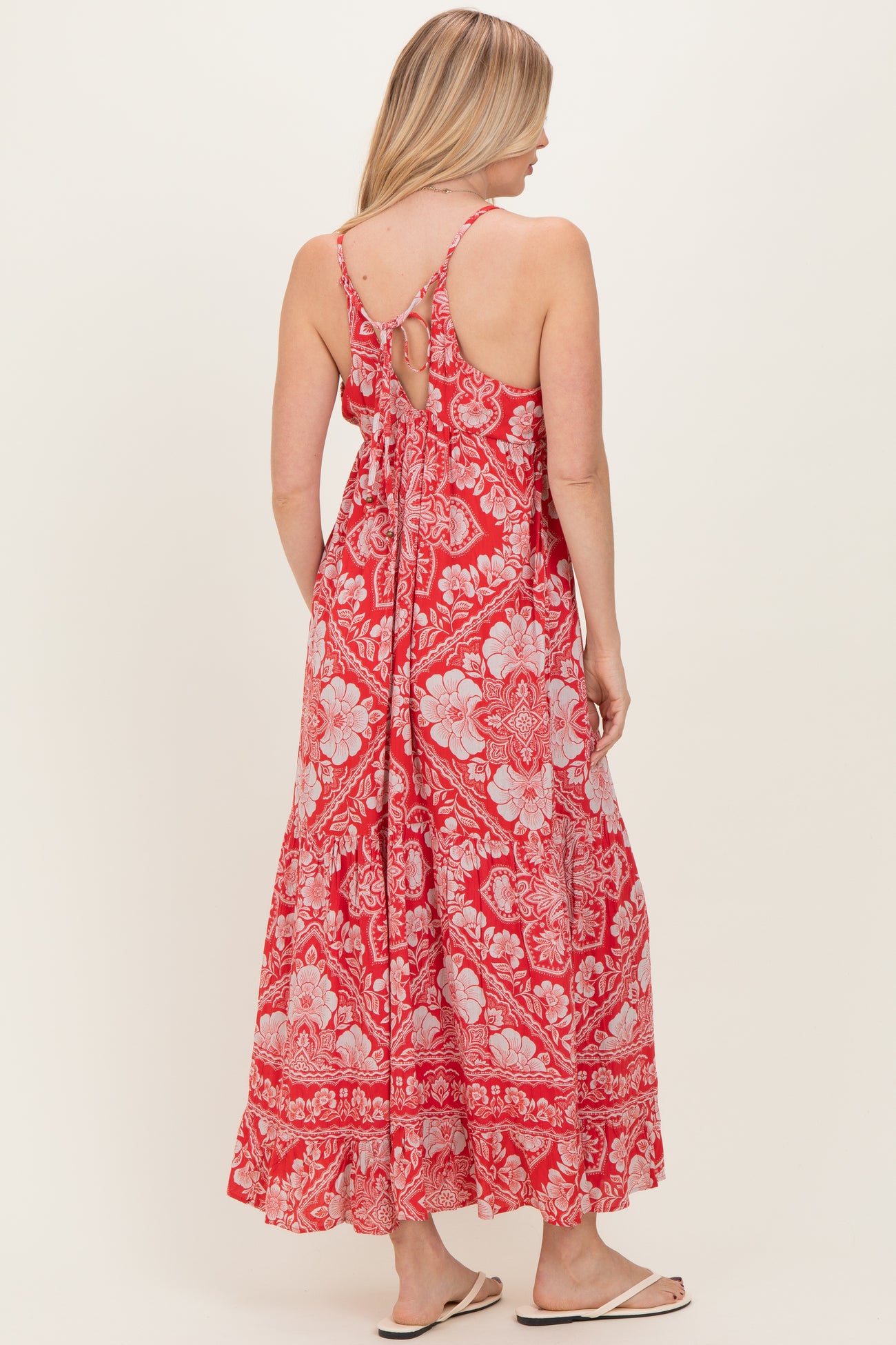 woman wearing a red floral maxi dress with a tie back and adjustable straps, showing the back view