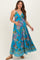 woman wearing a blue floral maxi maternity dress and gently cradling her baby bump
