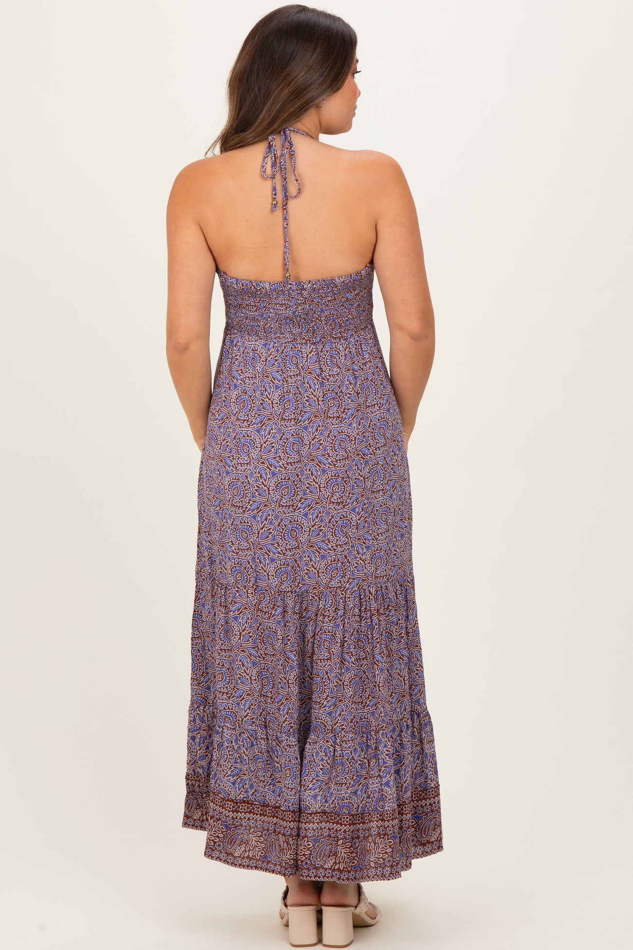 woman wearing a purple floral maternity maxi dress with a smocked back and tie straps
