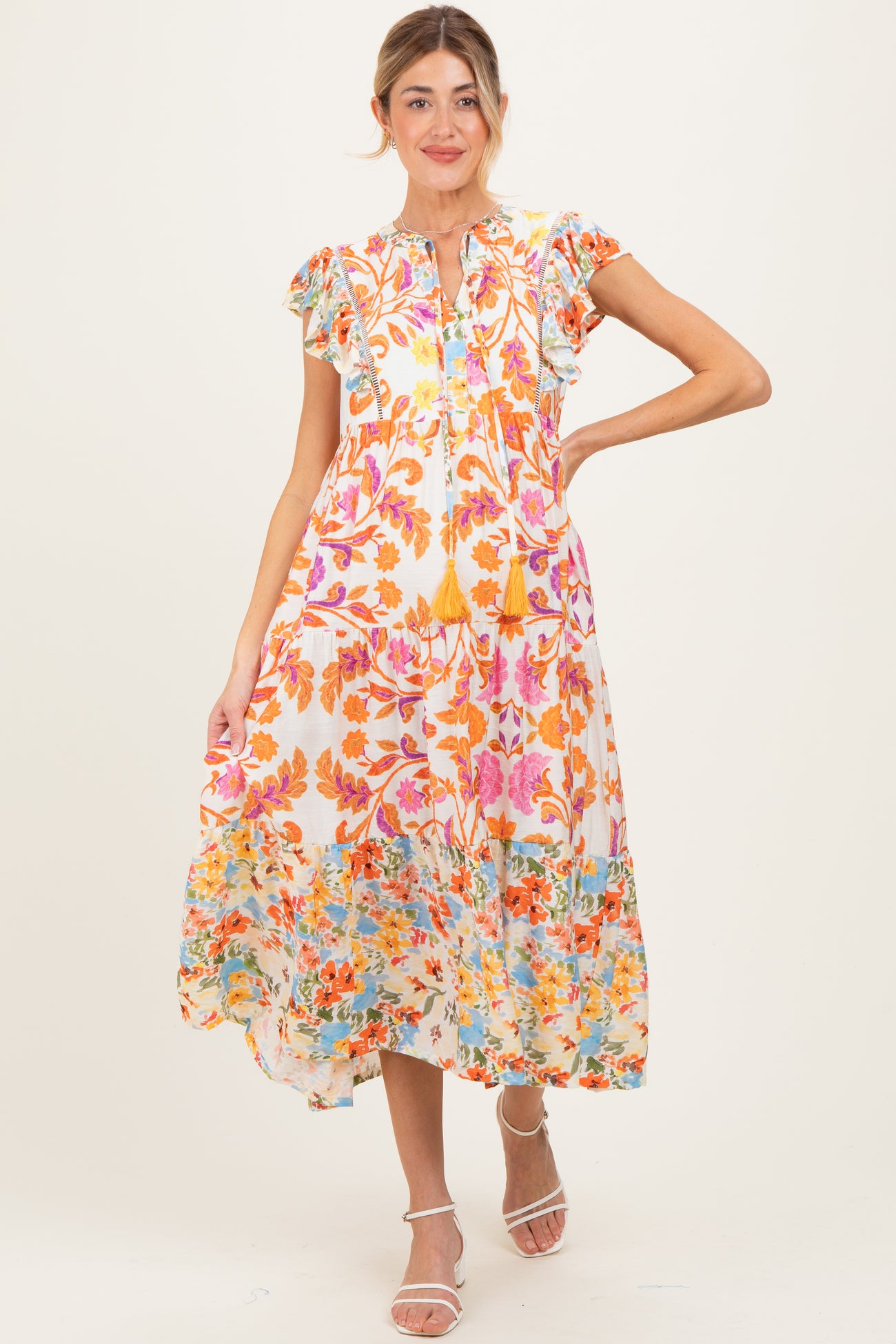 woman wearing a floral patterned maternity dress with short ruffled sleeves and a tiered skirt