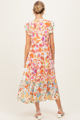 woman wearing a floral print maternity maxi dress with ruffled sleeves and a flowing skirt, showing a baby bump