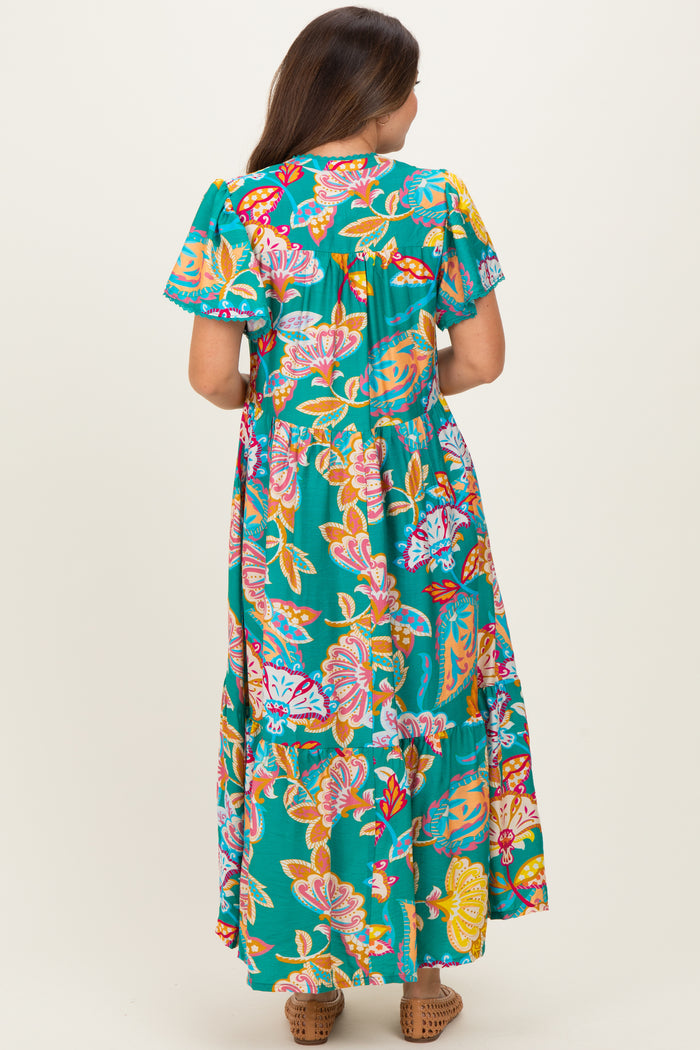 woman wearing a floral maxi dress in teal with ruffled sleeves, showcasing the back view.