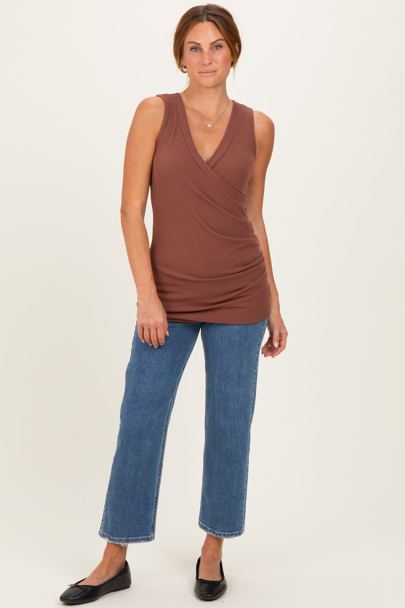 woman wearing a brown sleeveless wrap top paired with blue wide-leg jeans and black flats