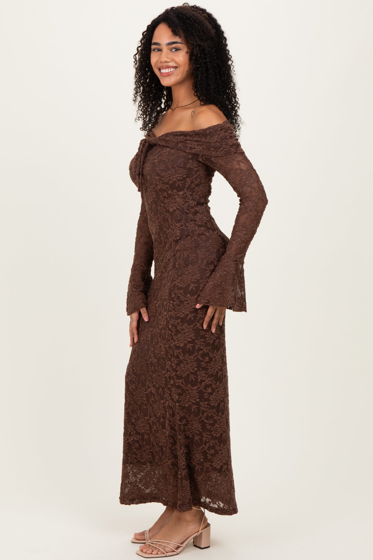 woman wearing a brown off-the-shoulder lace maxi dress with bell sleeves and a fitted silhouette