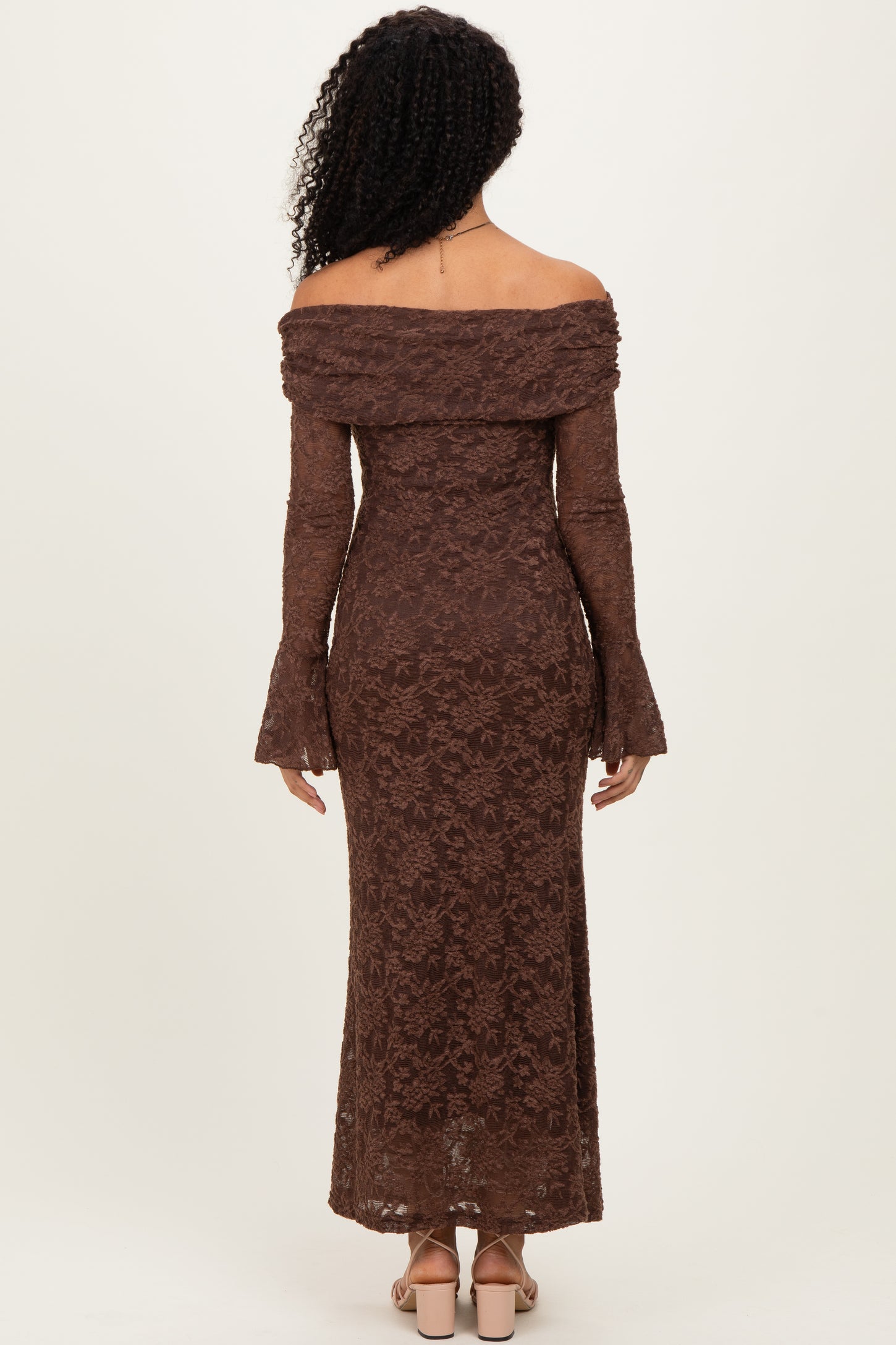 woman wearing a brown off-the-shoulder lace dress with bell sleeves, showing the back view