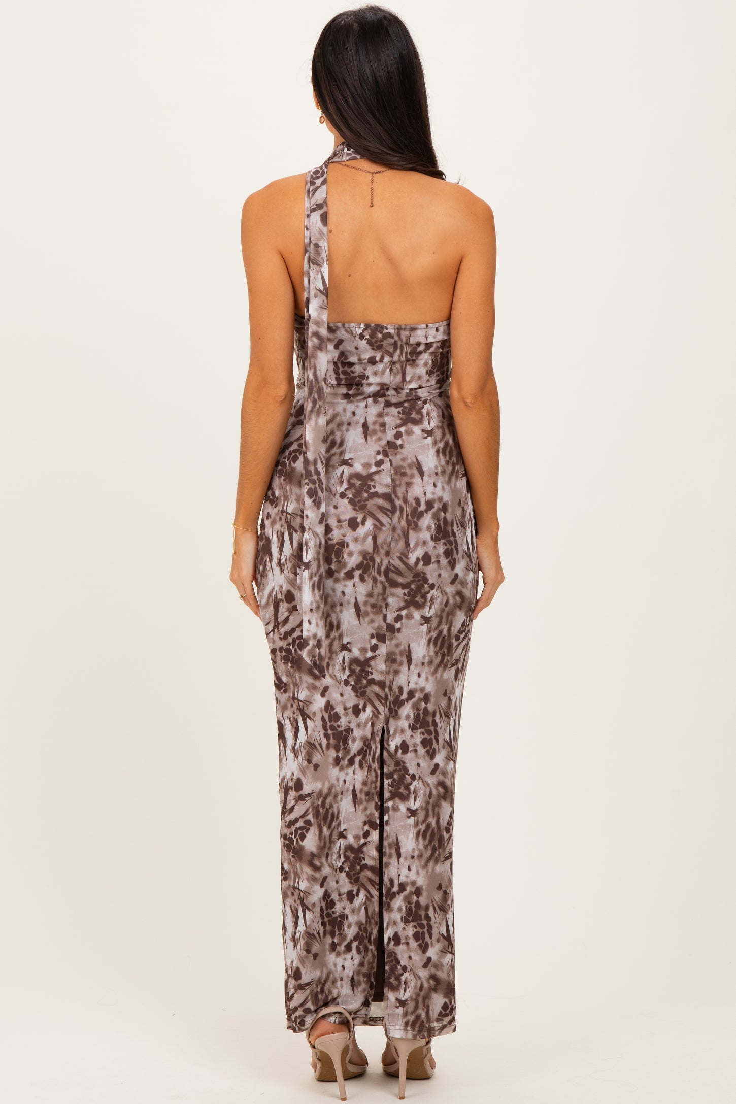 woman wearing a brown and beige patterned maxi dress with a one-shoulder design and a side slit