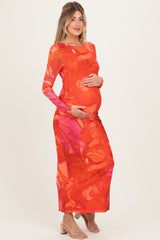 woman wearing a vibrant orange and pink long sleeve maternity dress and holding her baby bump