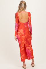 woman wearing a vibrant orange and pink long sleeve maternity dress with a low back and side slit