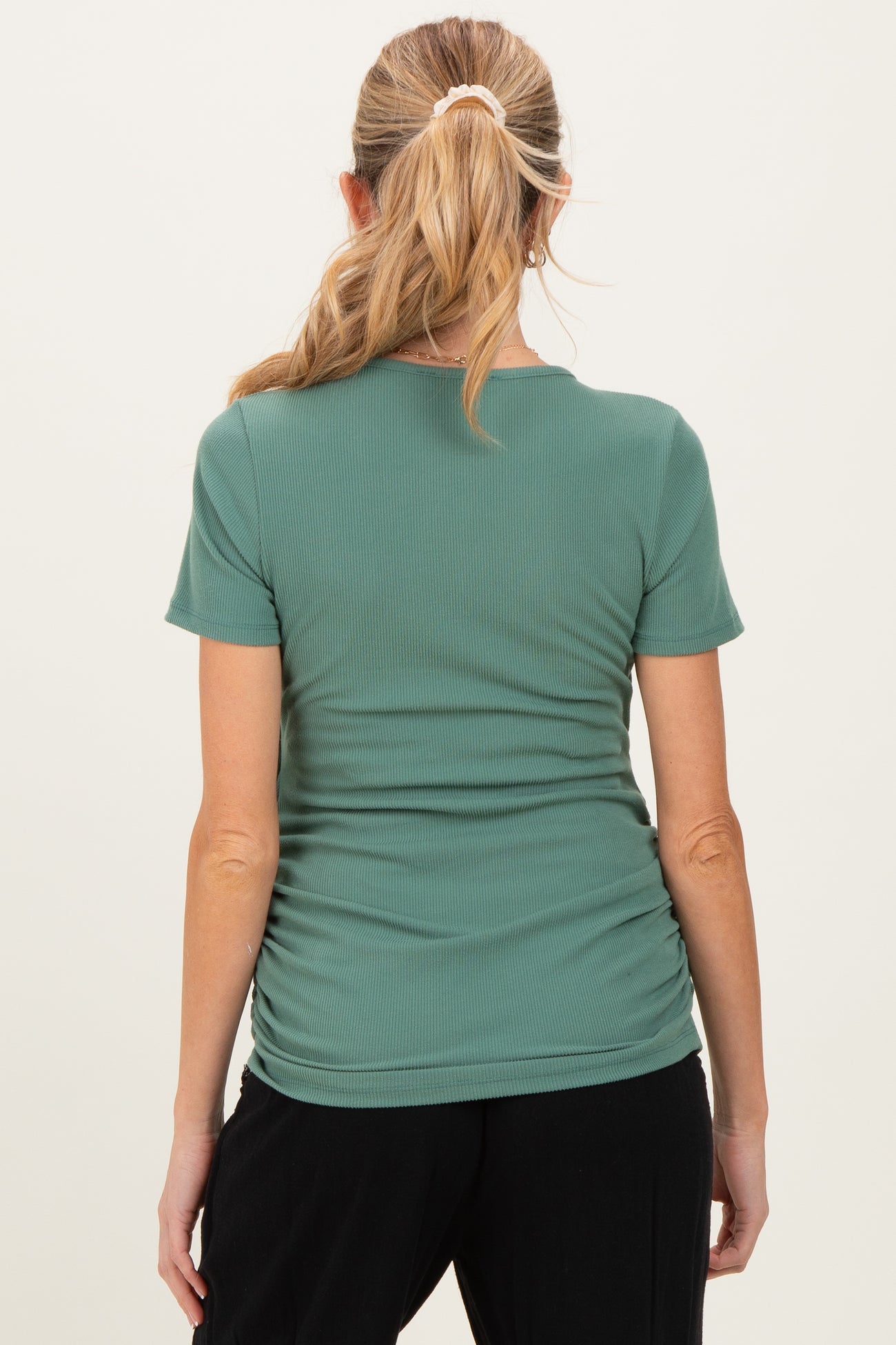 woman wearing a green maternity short sleeve top with ruching details on the sides