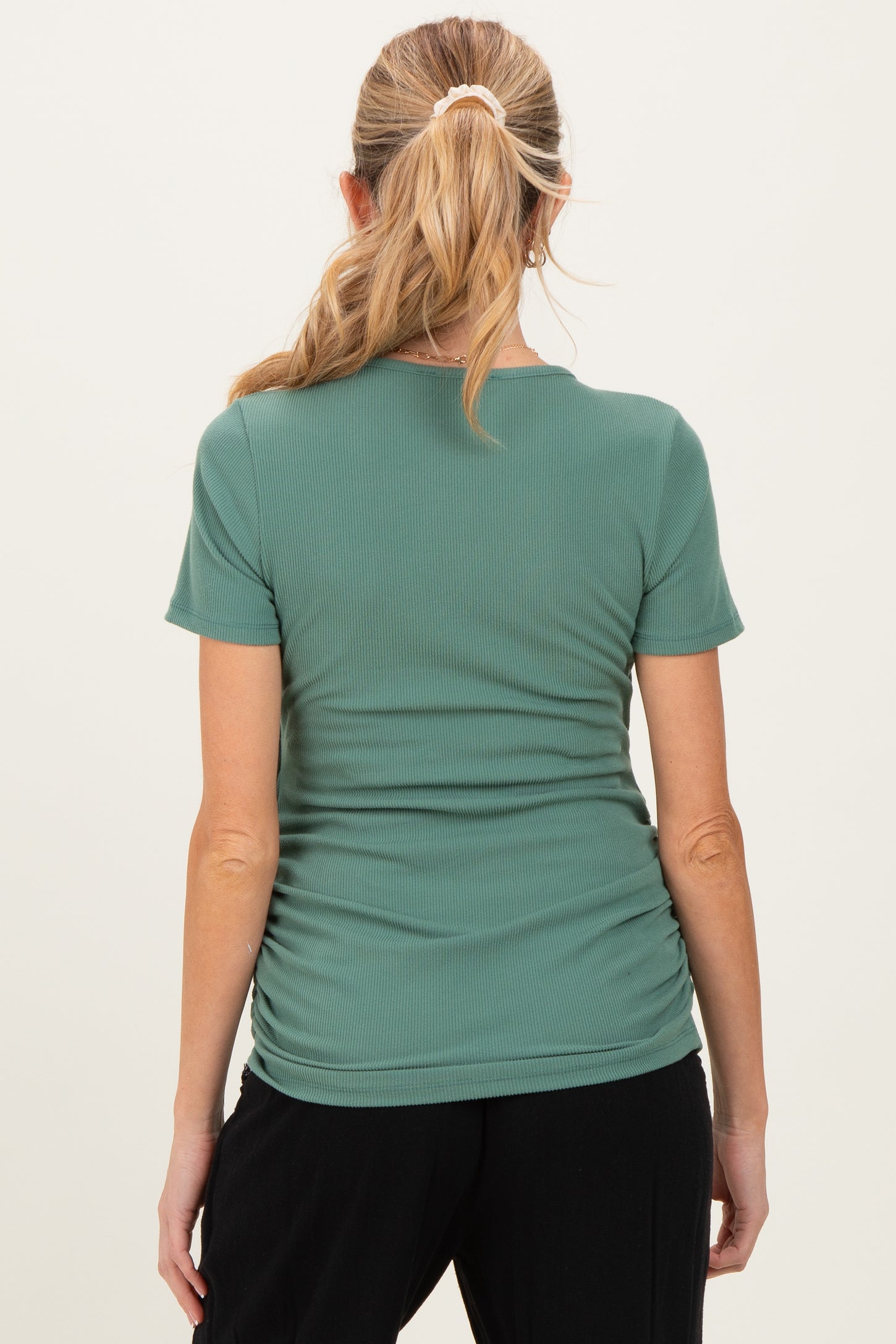 woman wearing a green maternity short sleeve top with ruching details on the sides