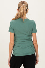 woman wearing a green maternity short sleeve top with ruching details on the sides